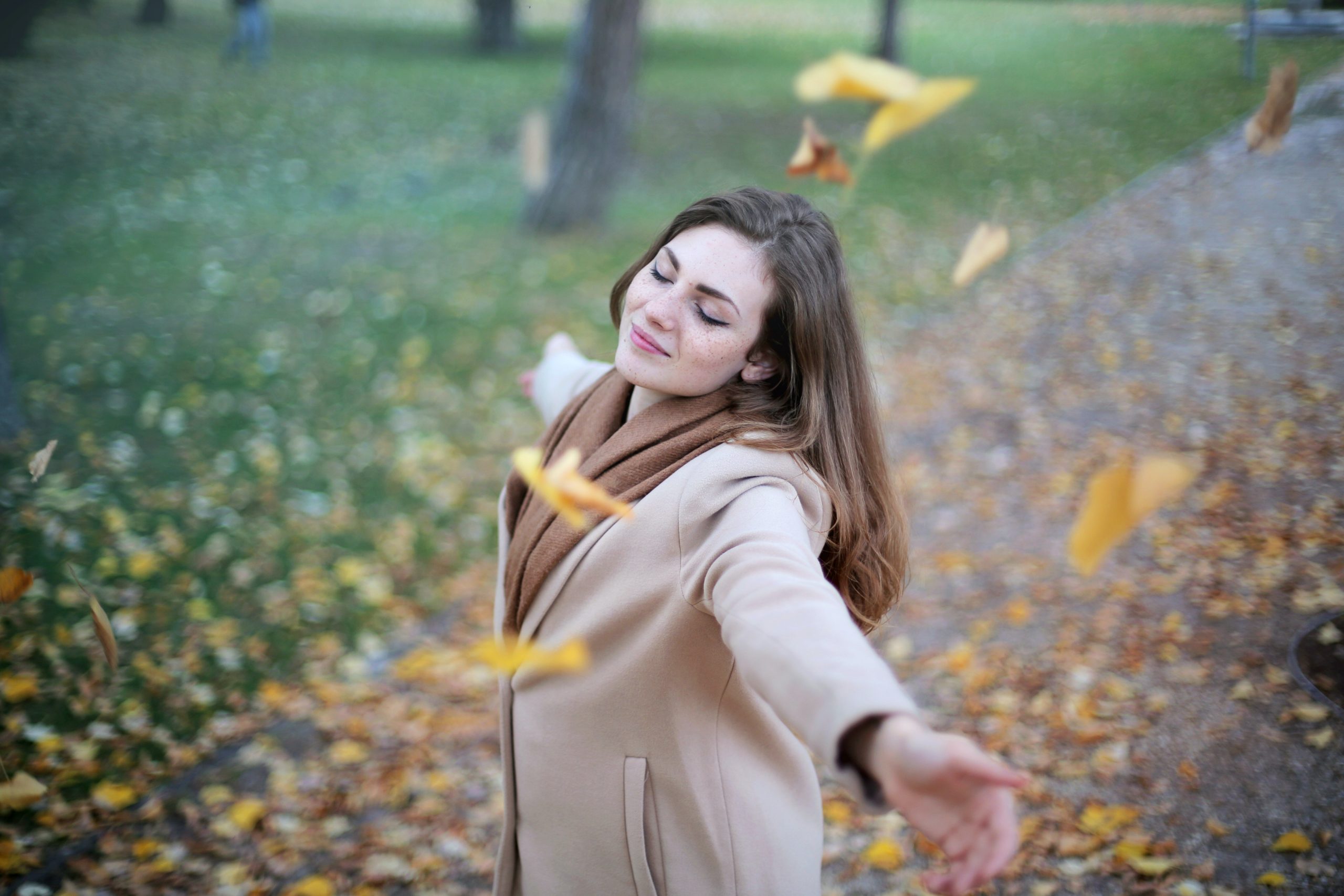 A woman enjoying a quiet moment outdoors among autumn leaves